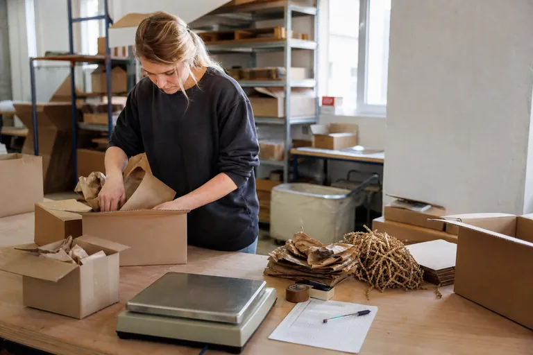 Packtisch mit Kartons, Füllmaterialien, Waage und einer Checkliste
